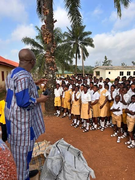 A speaker addressing a crowd of students under palm trees