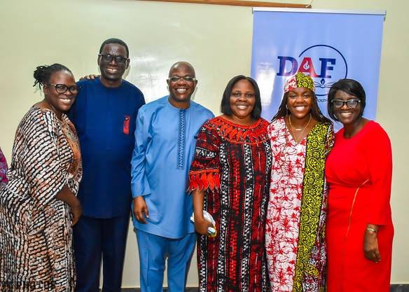 Foundation volunteers and guests standing in front of a Dele Awe Foundation banner